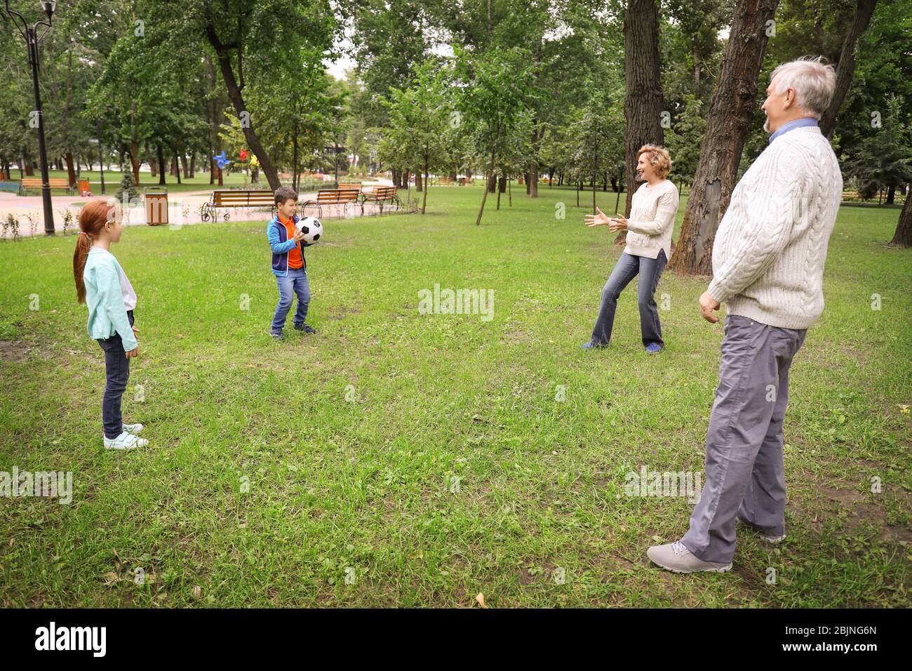 Senior man and woman playing with grandchildren in park Stock Photo