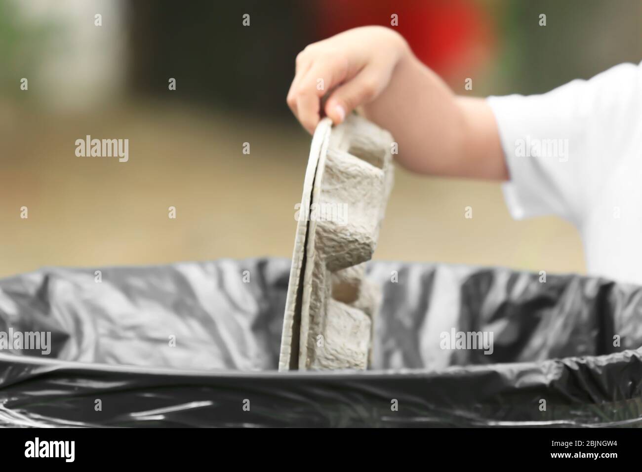 Hand of child throwing garbage into litter bin outdoors Stock Photo