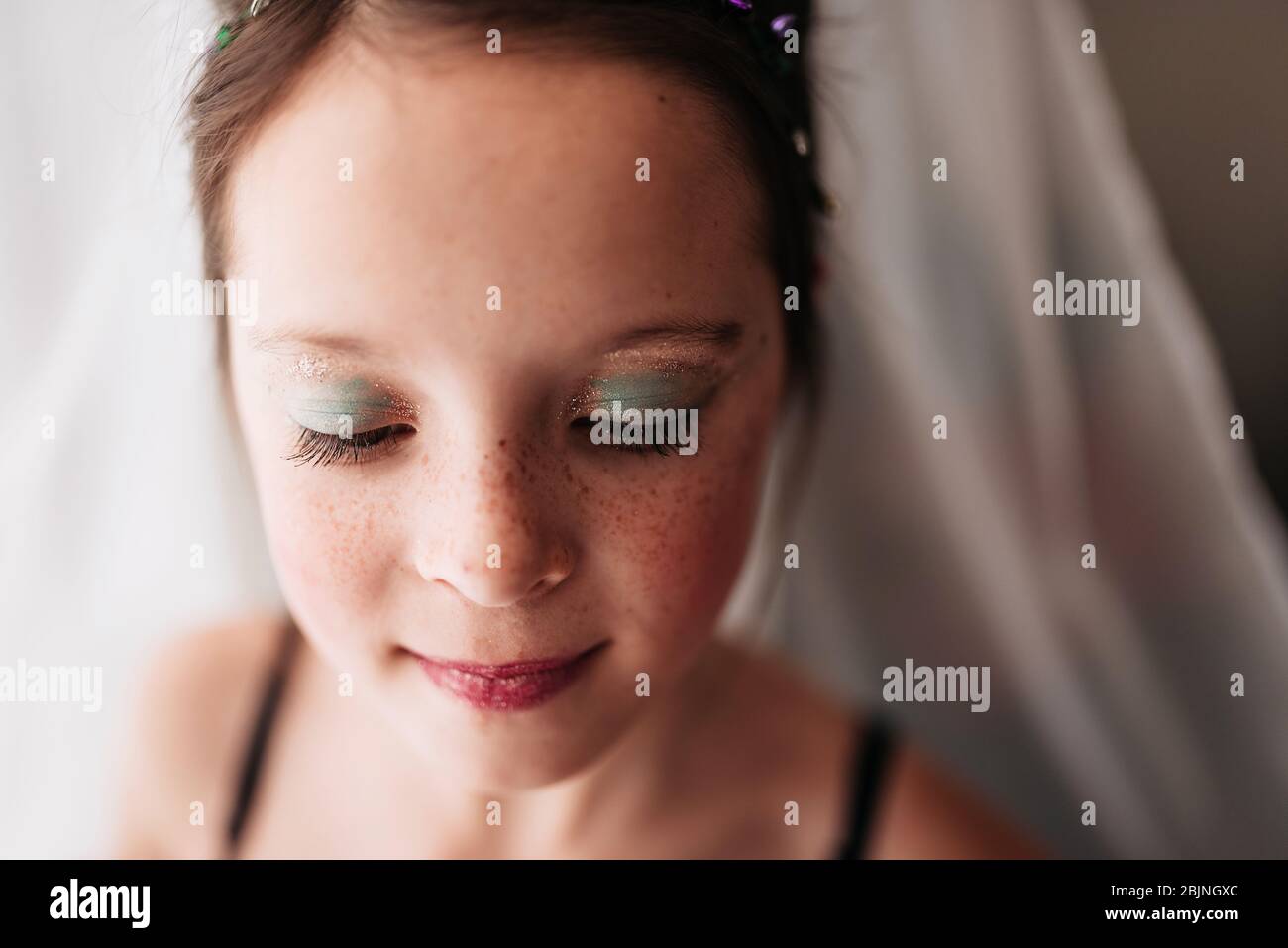 Portrait of a young girl wearing make-up standing by a curtain Stock Photo