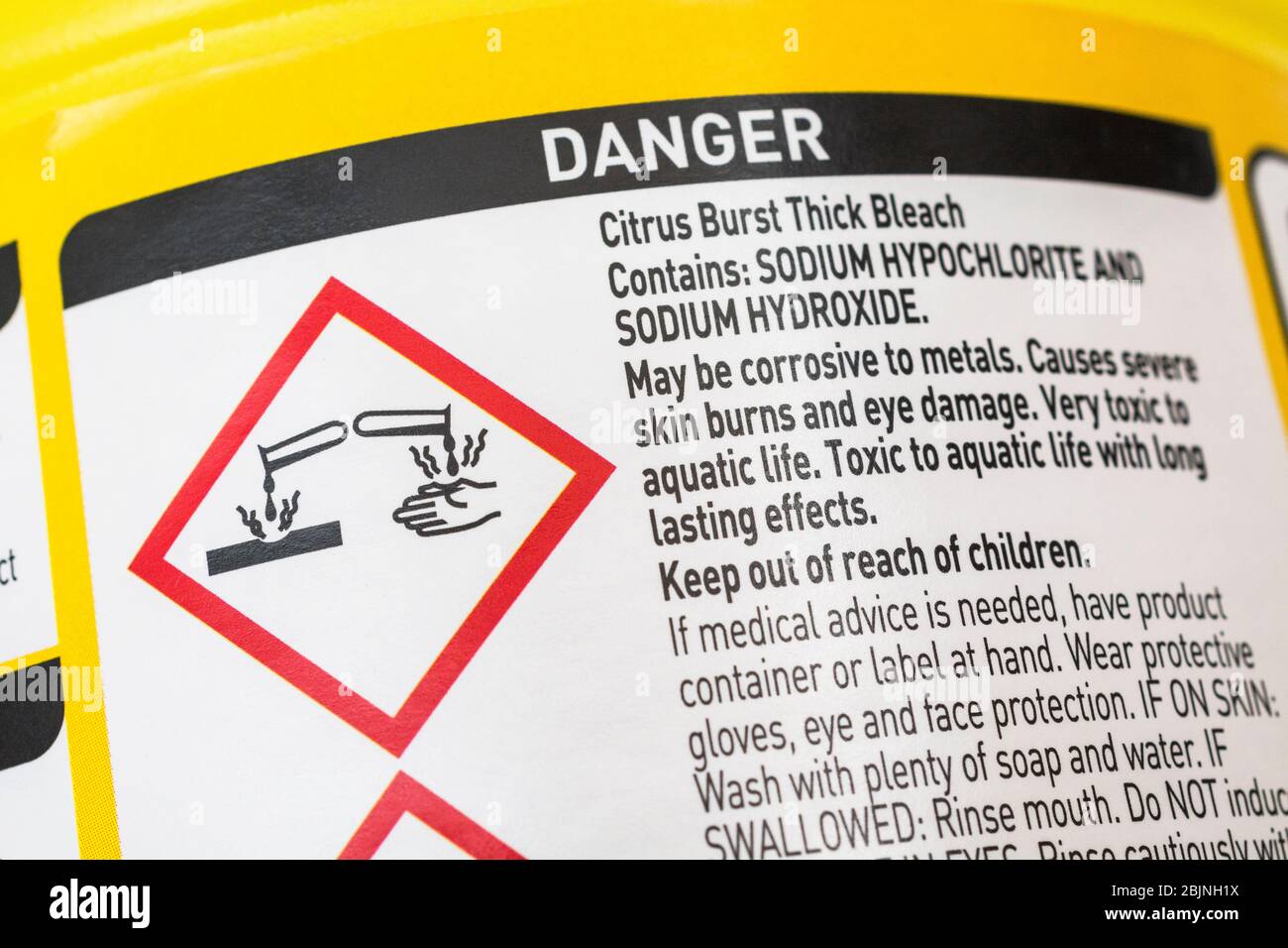 ASDA thick domestic bleach warning label with GHS 'materials causing skin burns / metal corrosion' icon pictogram. Dangerous household products. Stock Photo