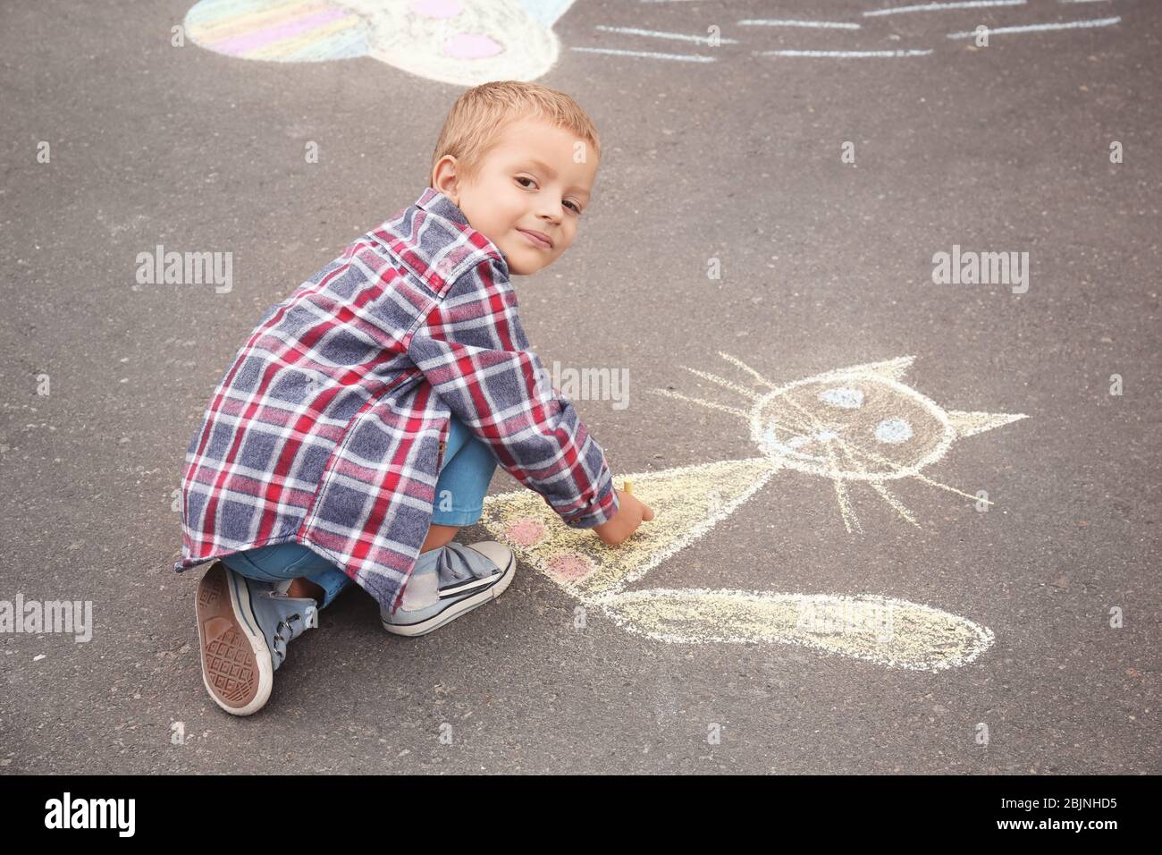 Little boy drawing cat with chalk on asphalt Stock Photo - Alamy