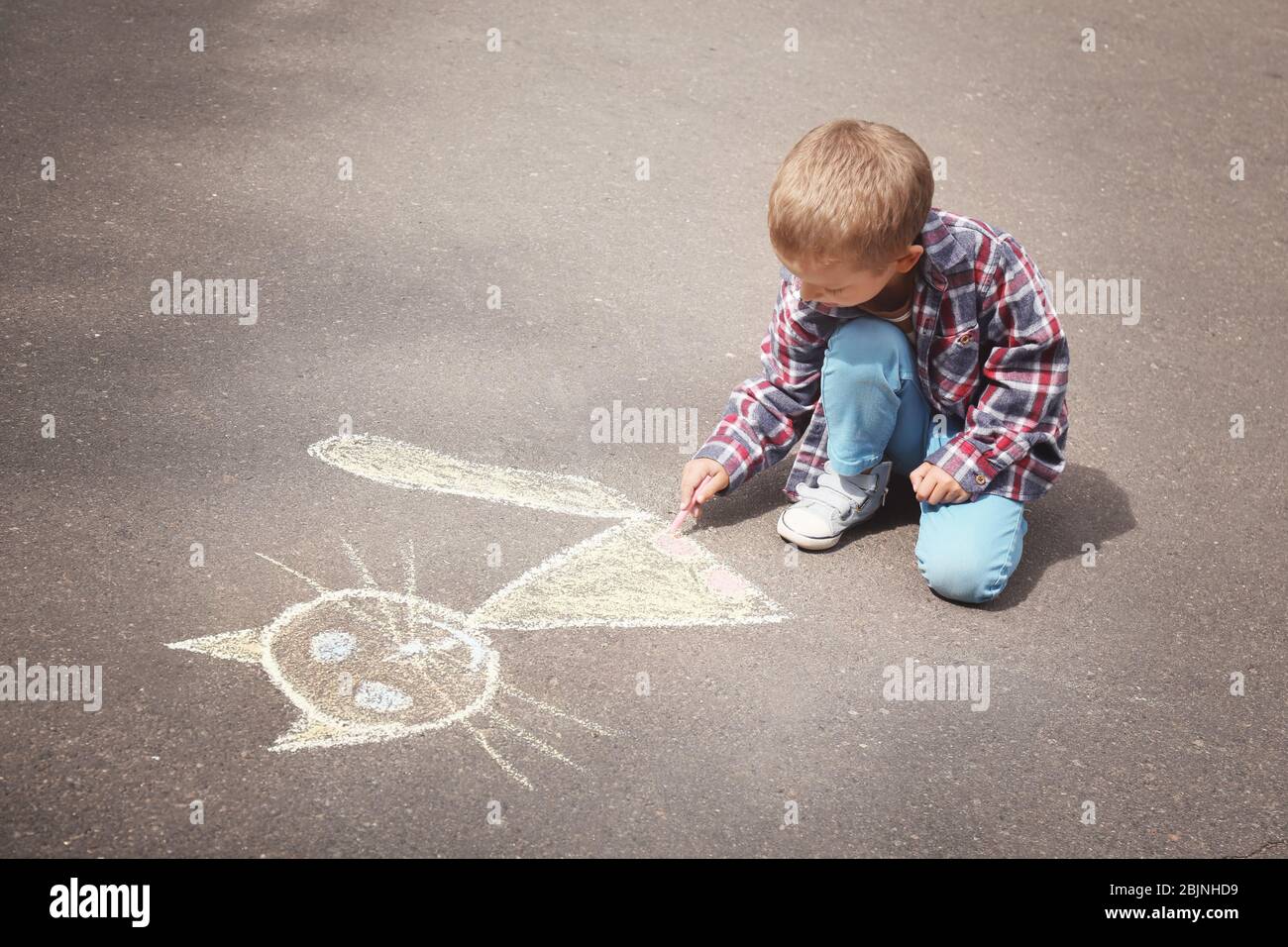 Little boy drawing cat with chalk on asphalt Stock Photo - Alamy