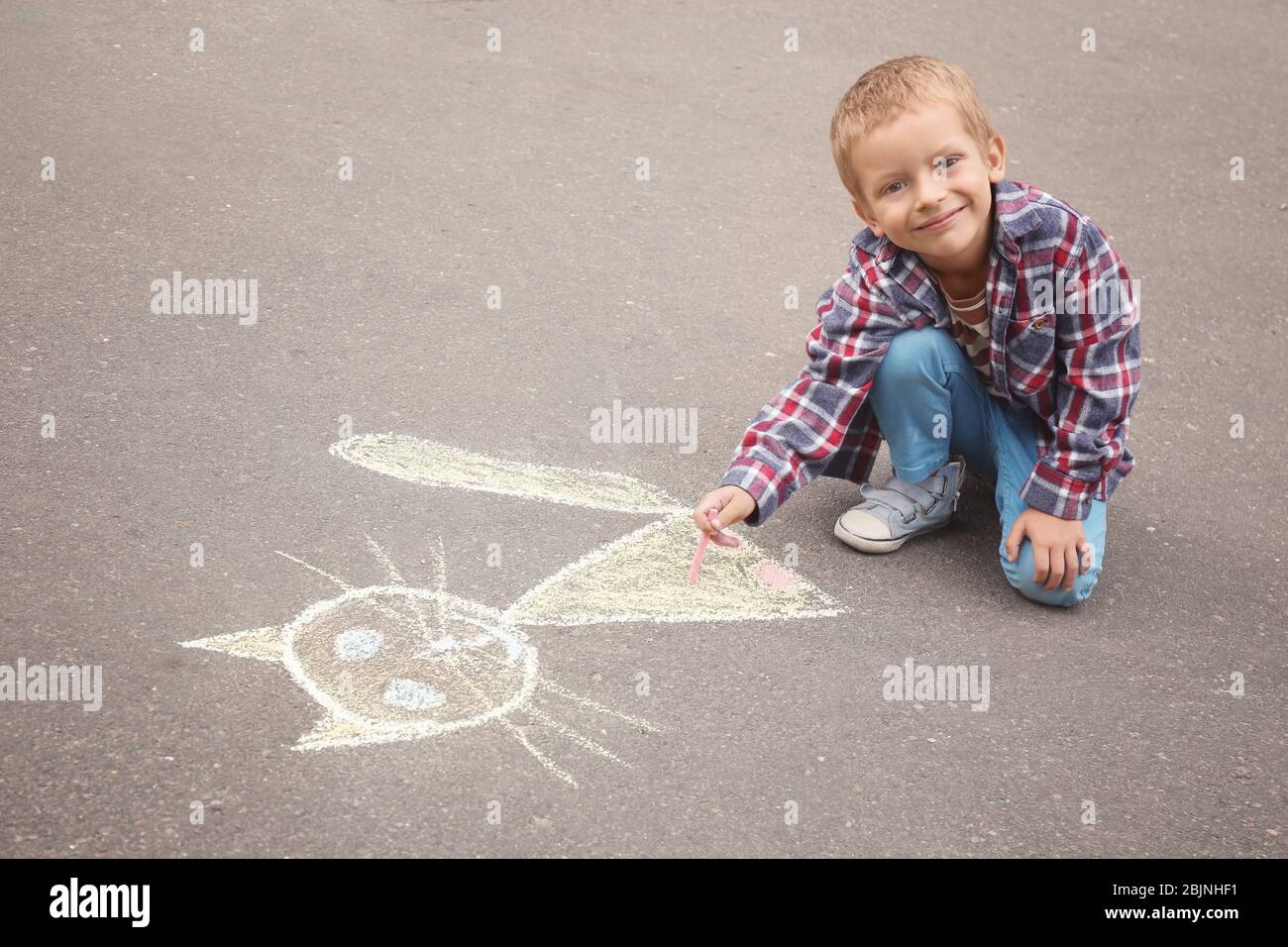 Little boy drawing cat with chalk on asphalt Stock Photo - Alamy