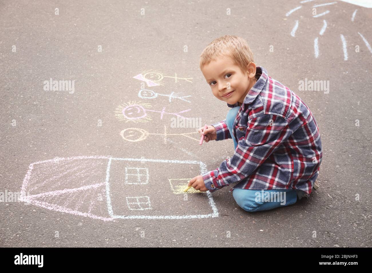 Little boy drawing house and family with chalk on asphalt Stock Photo ...