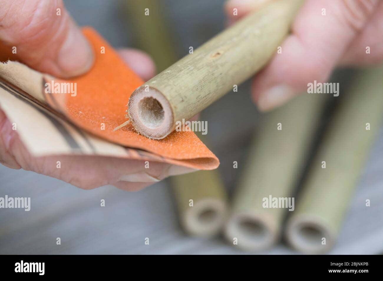 nesting aid for wild bees, step two: smoothing bamboo with emery paper Stock Photo