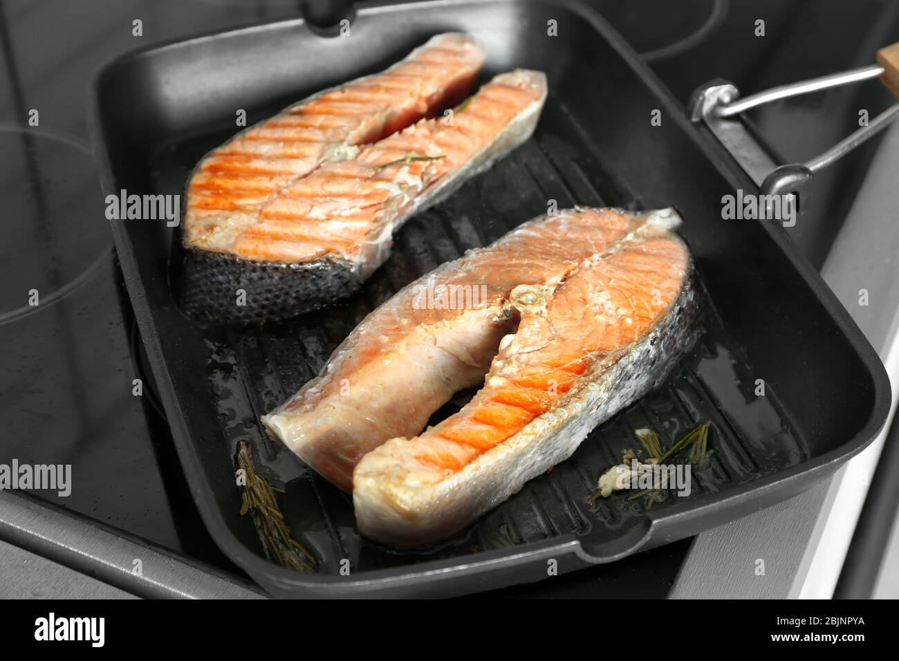 Grill pan with delicious salmon steaks on stove in kitchen Stock