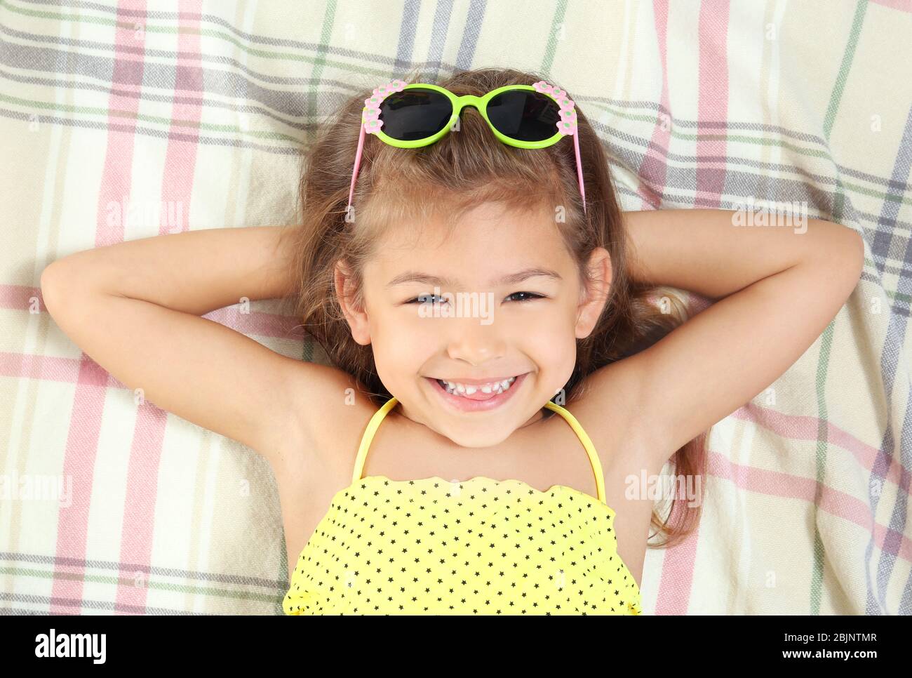 Adorable little girl in swimsuit lying on beach blanket Stock Photo Alamy