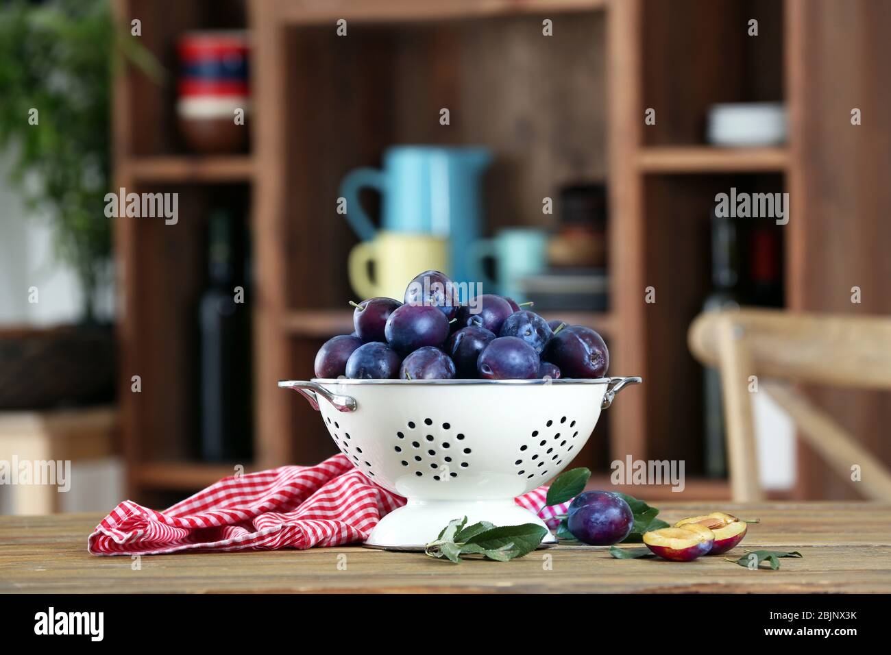 Fresh plums in colander on table Stock Photo