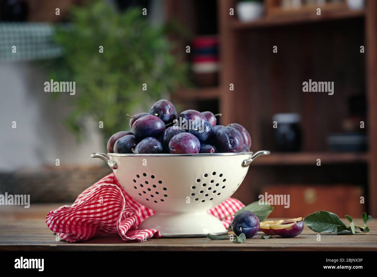 Fresh plums in colander on table Stock Photo