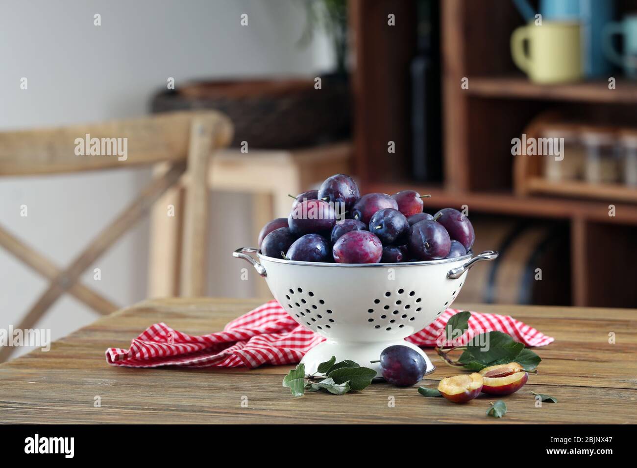 Fresh plums in colander on table Stock Photo