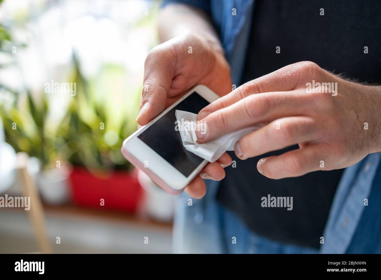 Man using a disinfection wipe on a phone Stock Photo