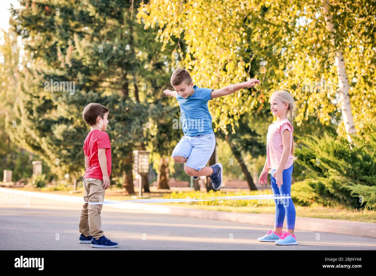 Adorable children playing elastic game outdoors Stock Photo - Alamy