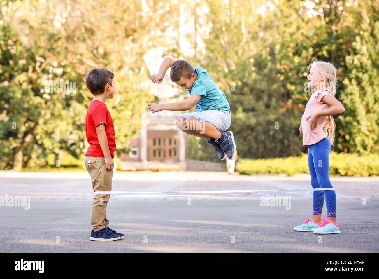 Adorable children playing elastic game outdoors Stock Photo Alamy