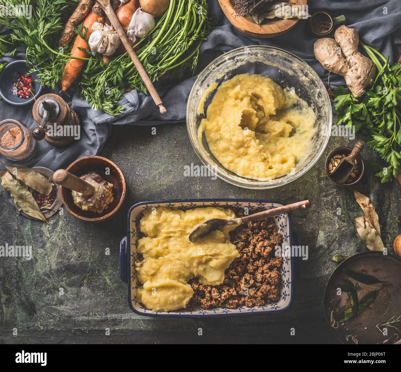 Mashed potato casserole with meat cooking. Ingredients on dark rustic kitchen table background. Top view. Tasty home cuisine. Stock Photo