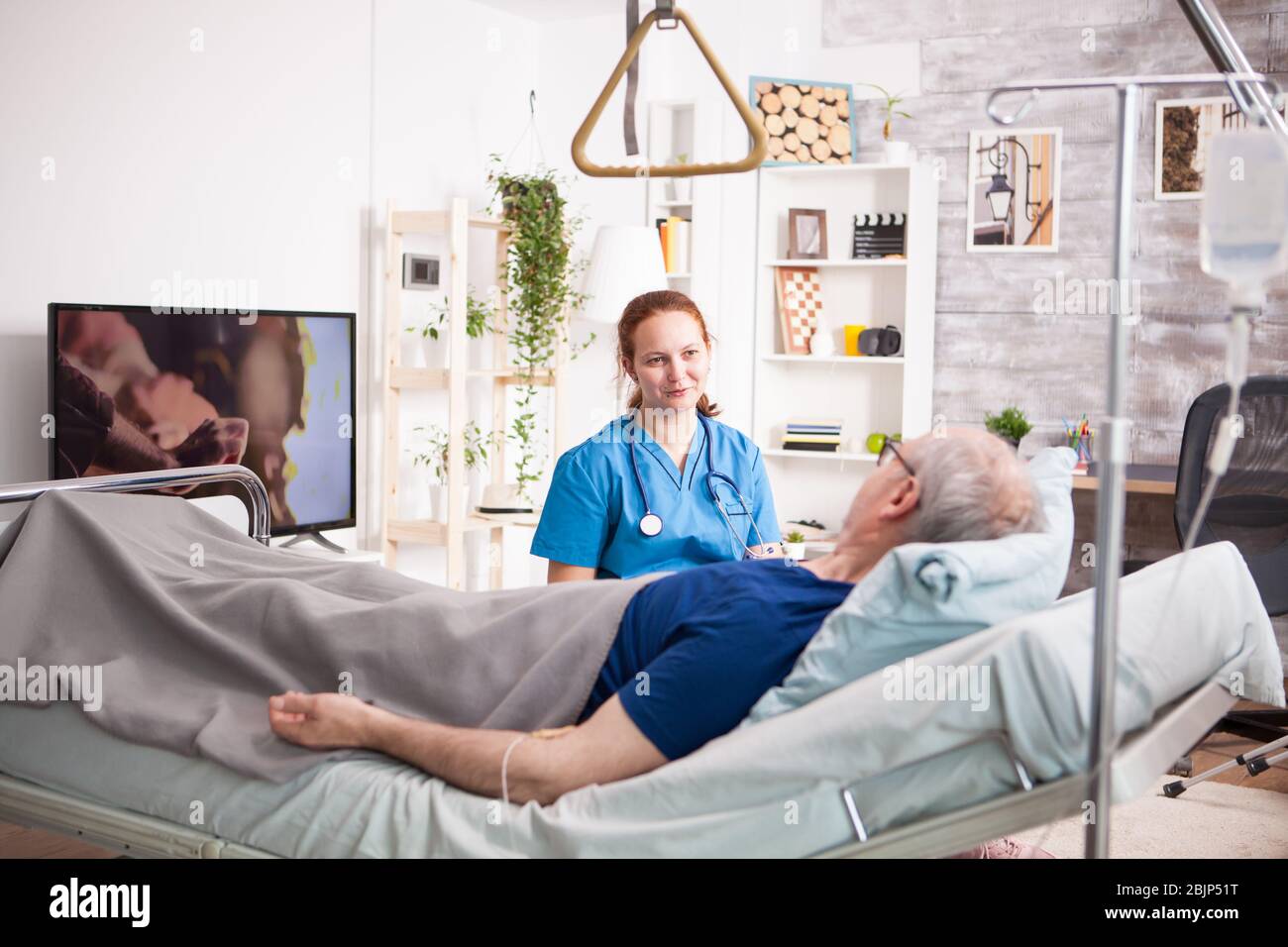Sick old man laying on bed in nursing home and talking with female