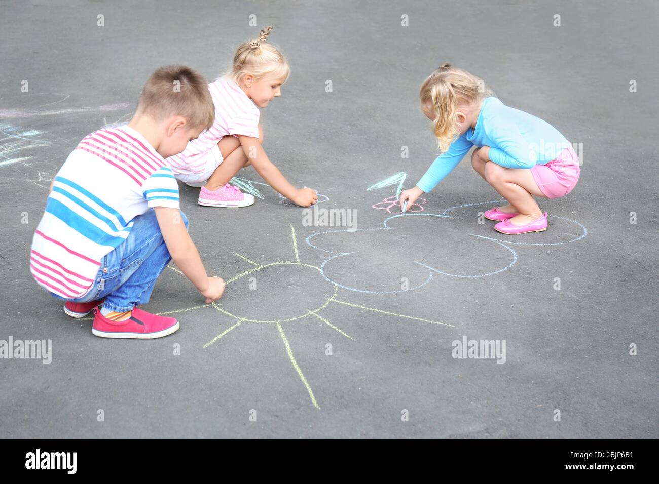 Cute little children drawing with chalk on asphalt Stock Photo - Alamy