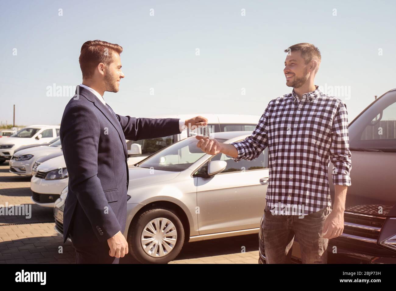 Salesman giving key to customer near new car outdoors Stock Photo - Alamy