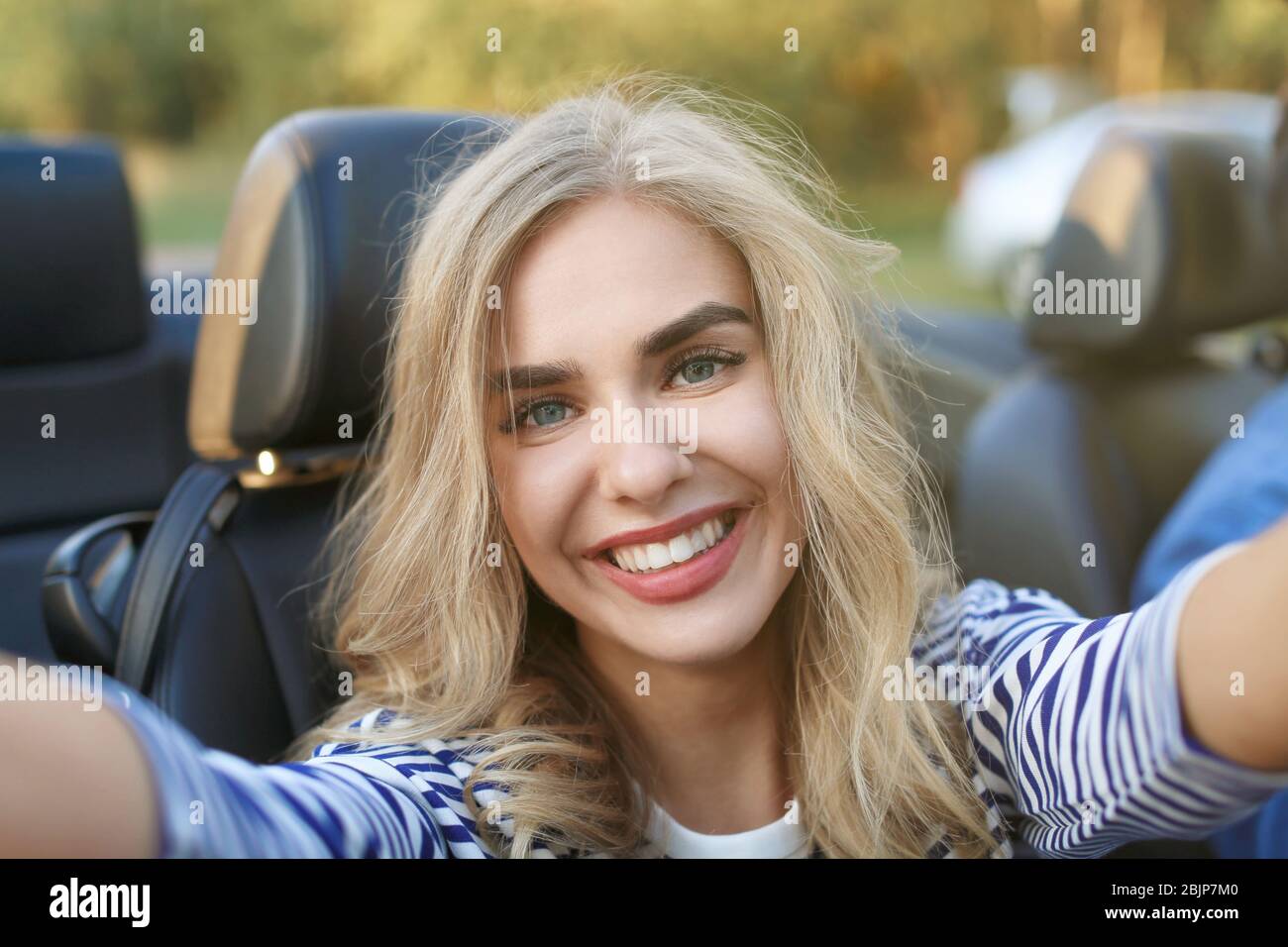 Beautiful young woman taking selfie in car Stock Photo - Alamy
