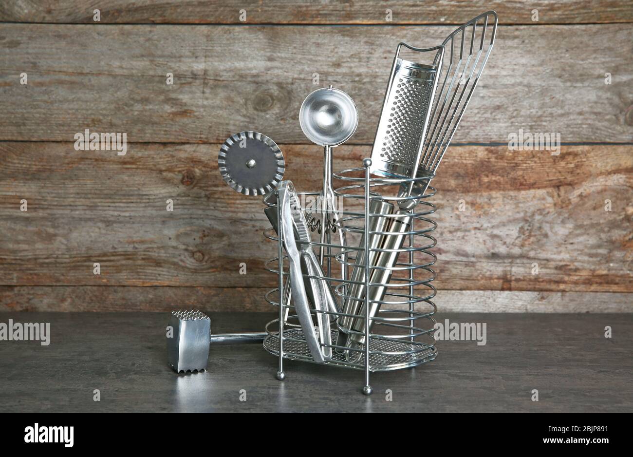 Stand with kitchen utensils on table against wooden wall Stock Photo - Alamy