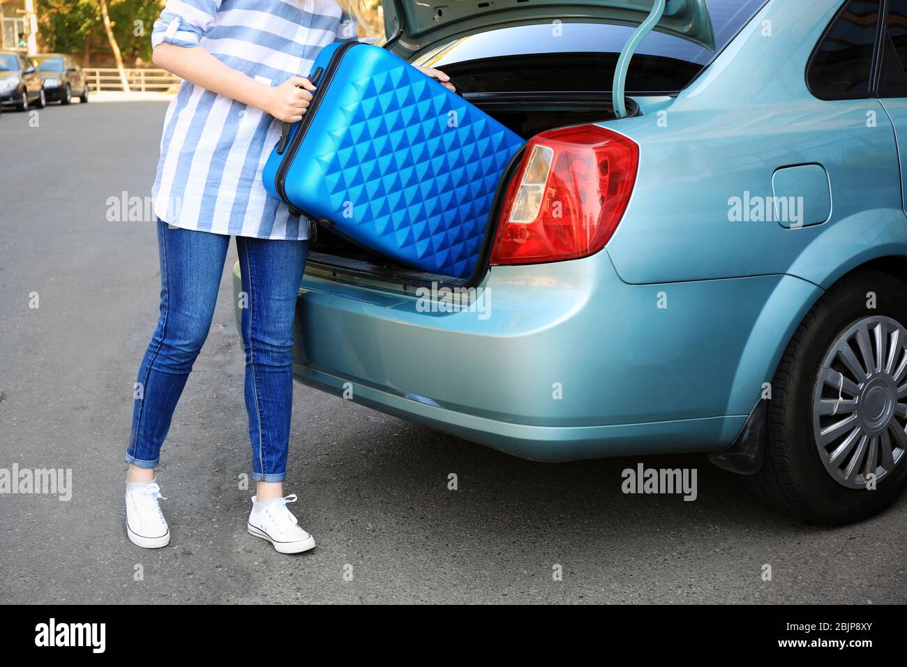 Woman putting her suitcase in taxi trunk Stock Photo Alamy