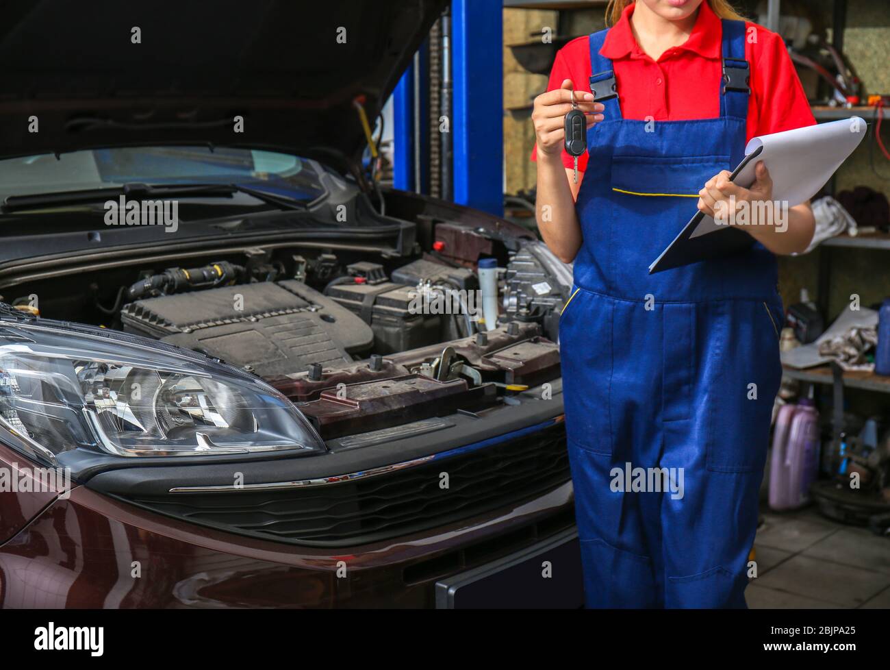 Young female mechanic with clipboard and car key in body shop Stock Photo
