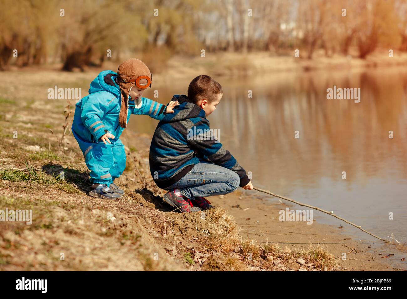 Friendly brothers on the river Bank look at the water. Family vacation Stock Photo