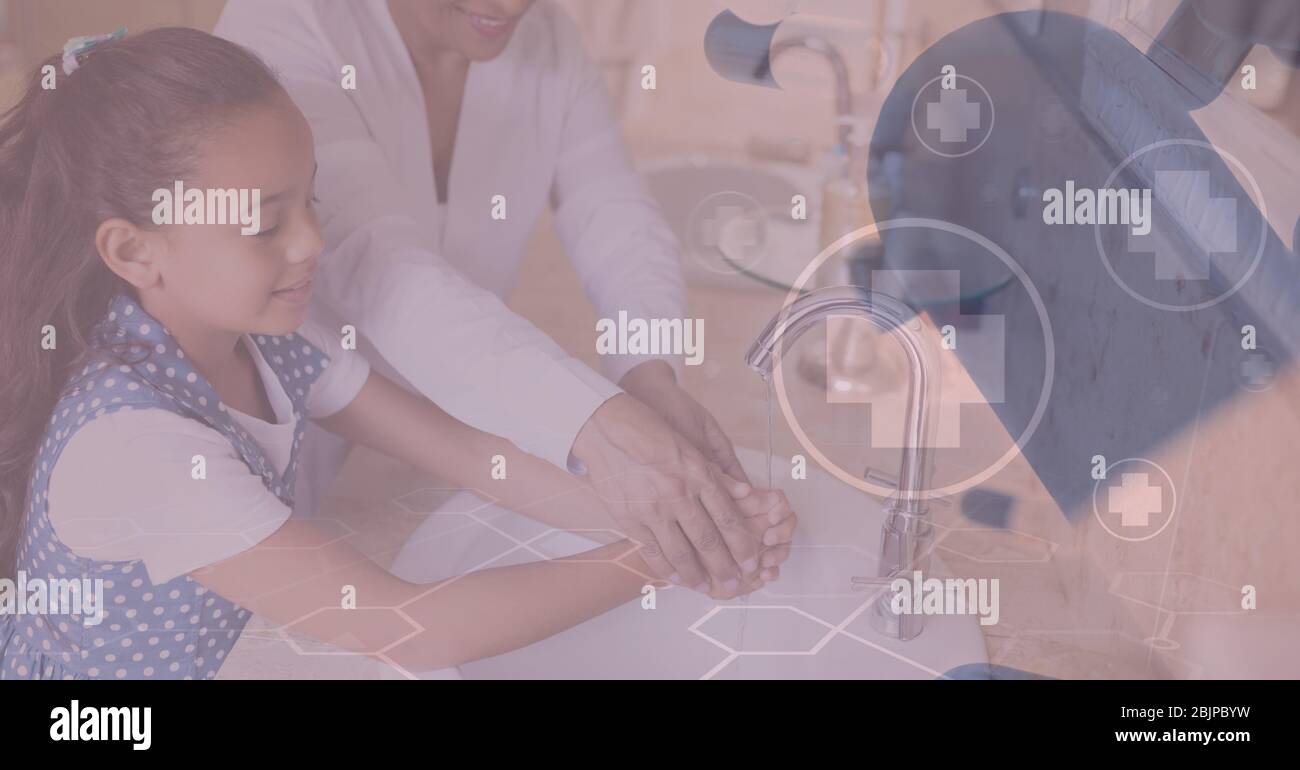 Digital illustration of medical icons over mother and her daughter washing hands together Stock Photo