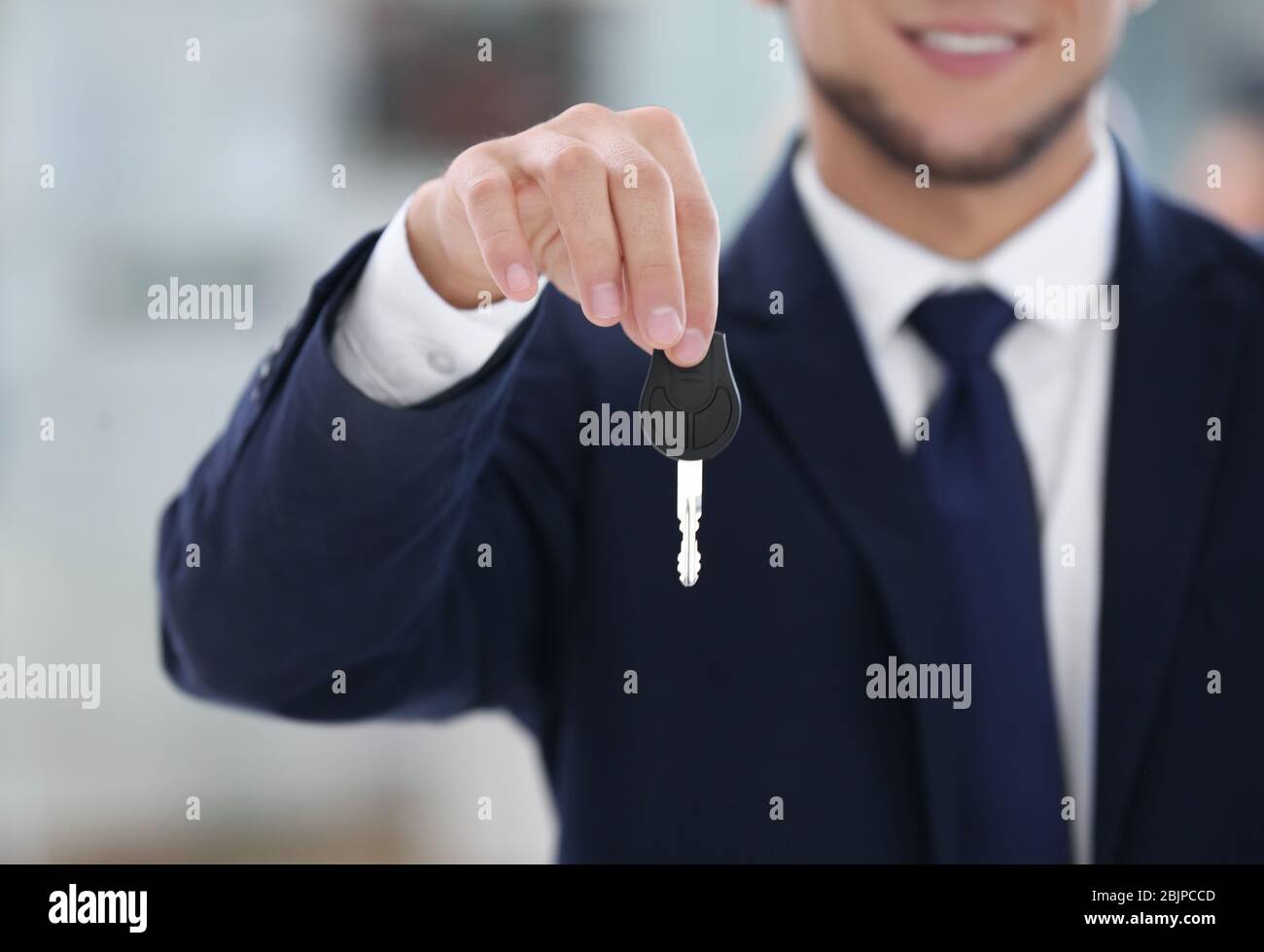 Car salesman holding key on blurred background Stock Photo - Alamy