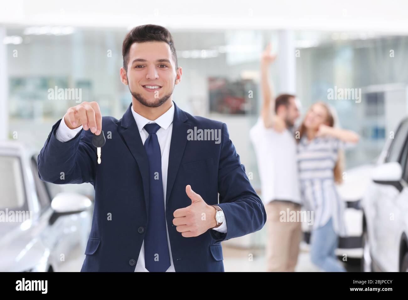 Car salesman holding key in dealership Stock Photo - Alamy