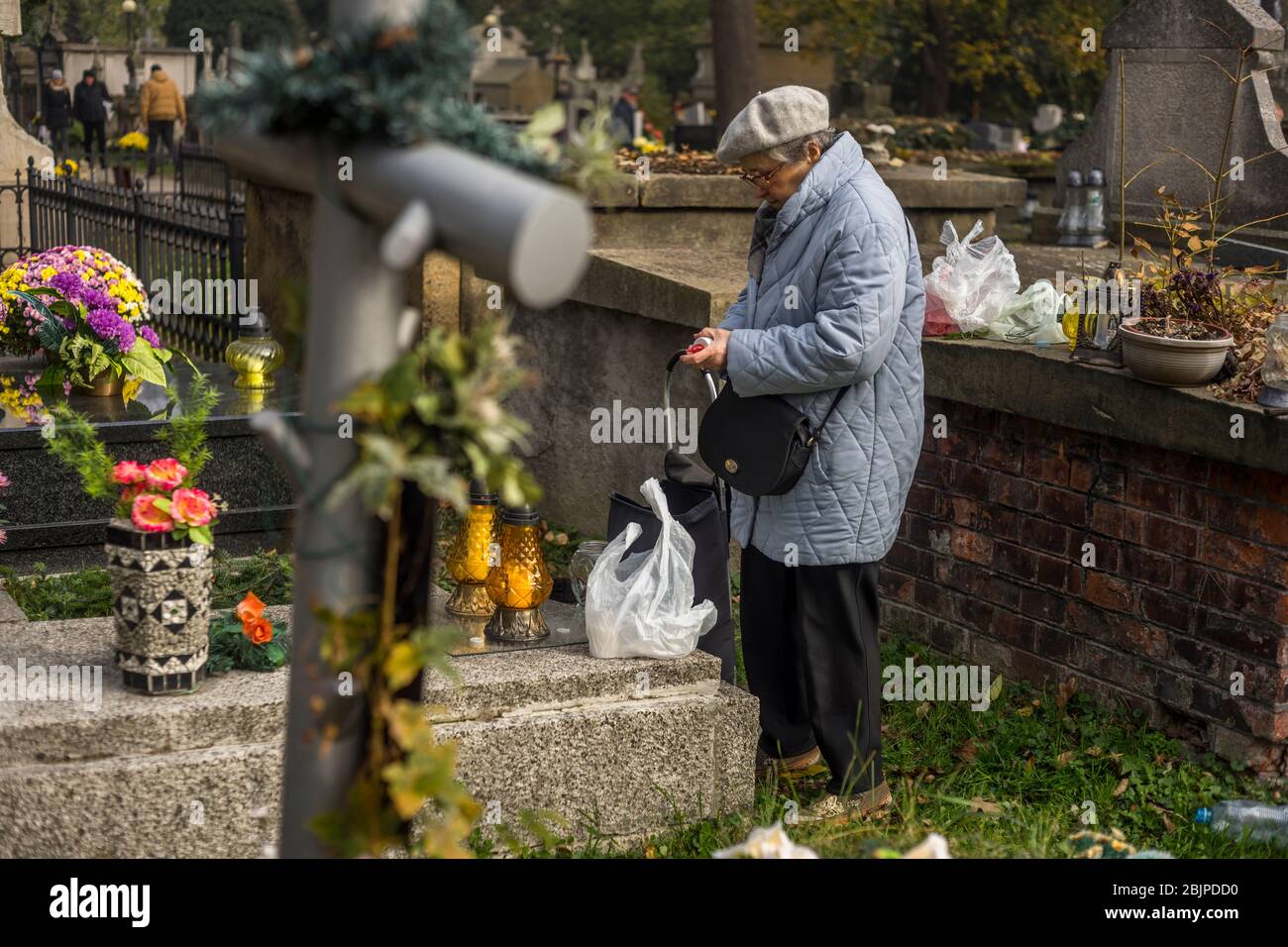 A woman lights a candle at Rakowicki cemetery in Krakow, Poland 2019