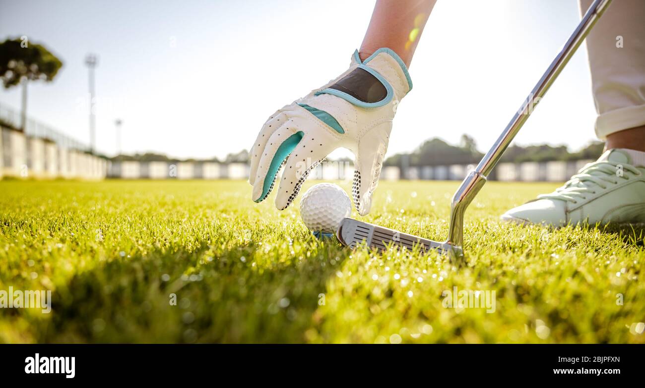 Hand in glove placing golf ball on tee Stock Photo