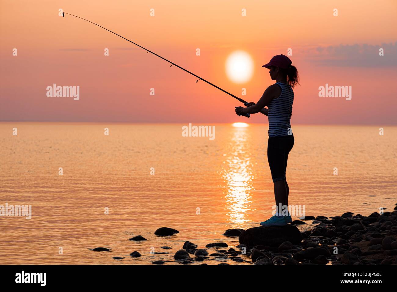 Woman fishing on Fishing rod spinning at sunset background Stock Photo -  Alamy