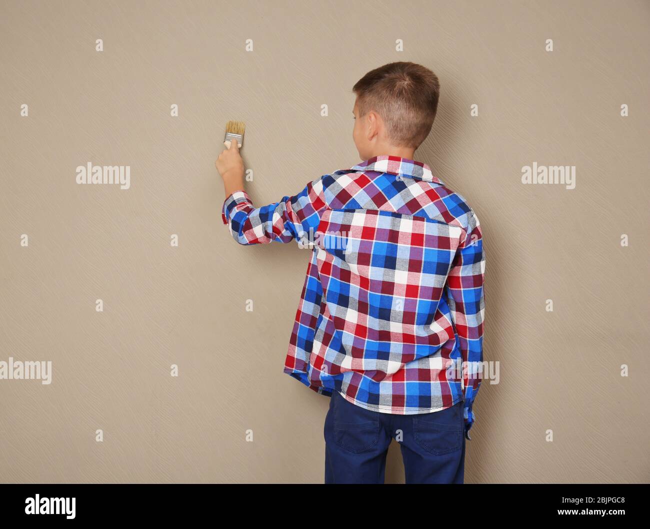 Cute little boy painting wall with brush Stock Photo Alamy