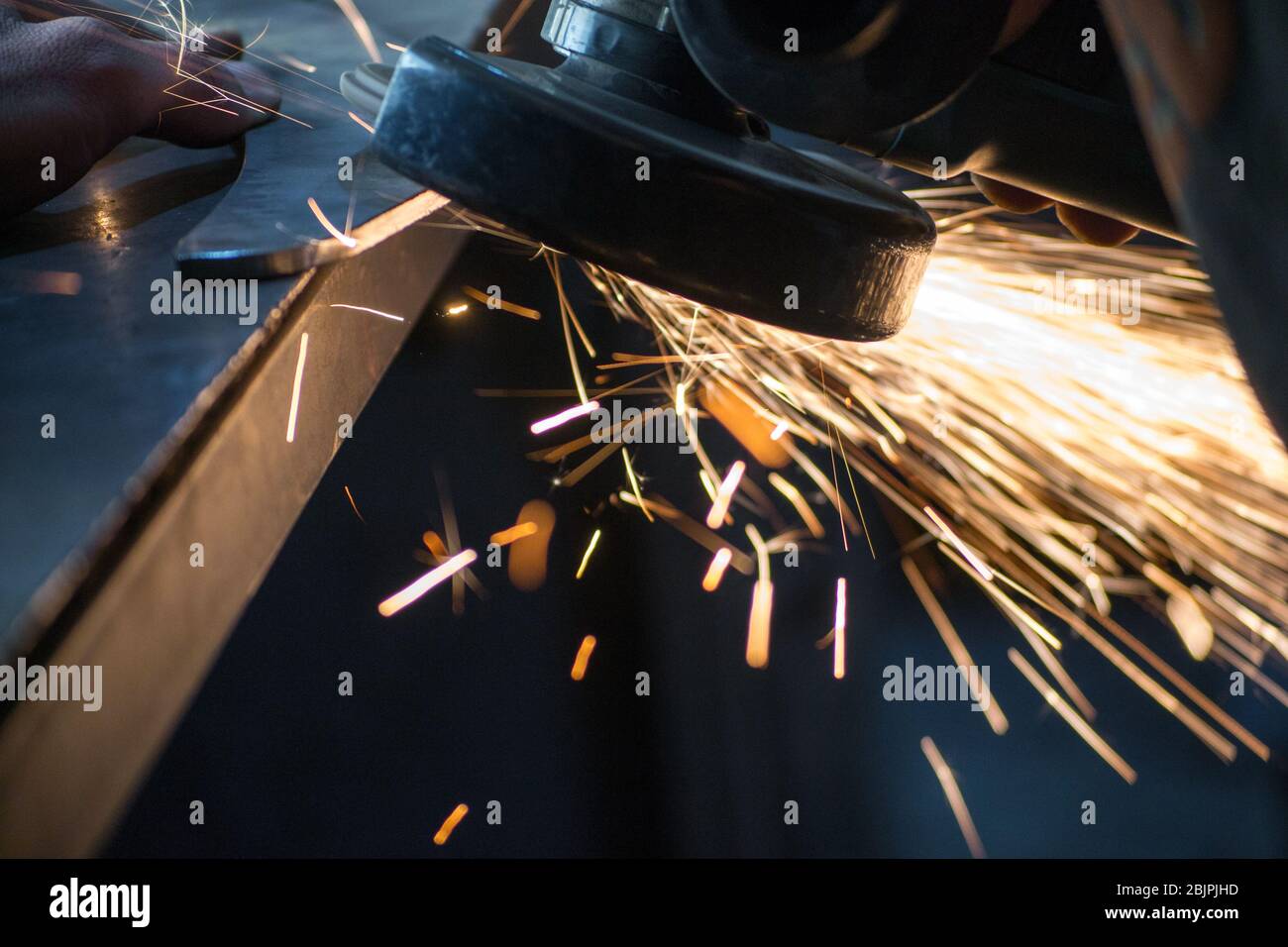 work with a manual grinder, flying sparks from grinding metal Stock