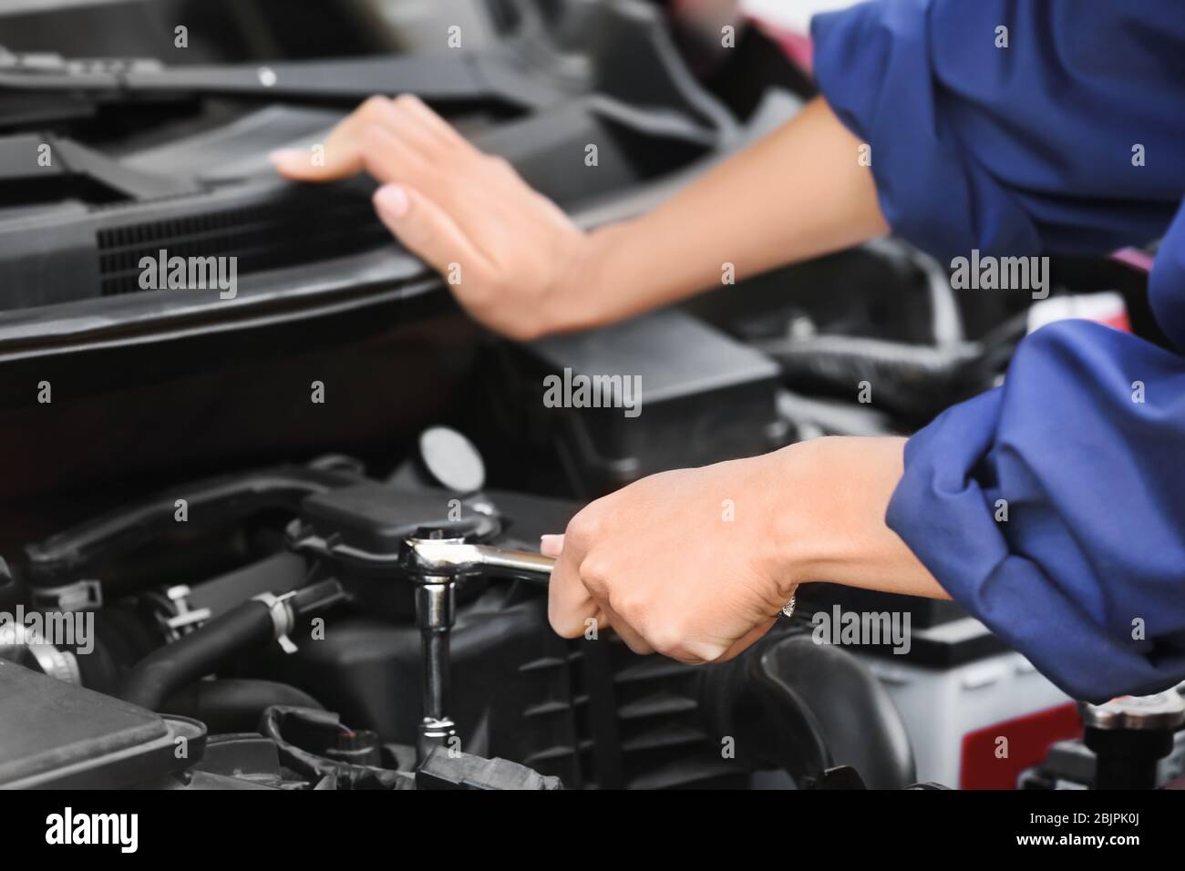 Young female mechanic repairing car in body shop Stock Photo