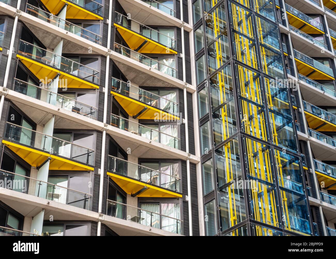 Modern flats. Full frame detail of a contemporary London apartment block with open balconies and a glass external lift shaft. Stock Photo