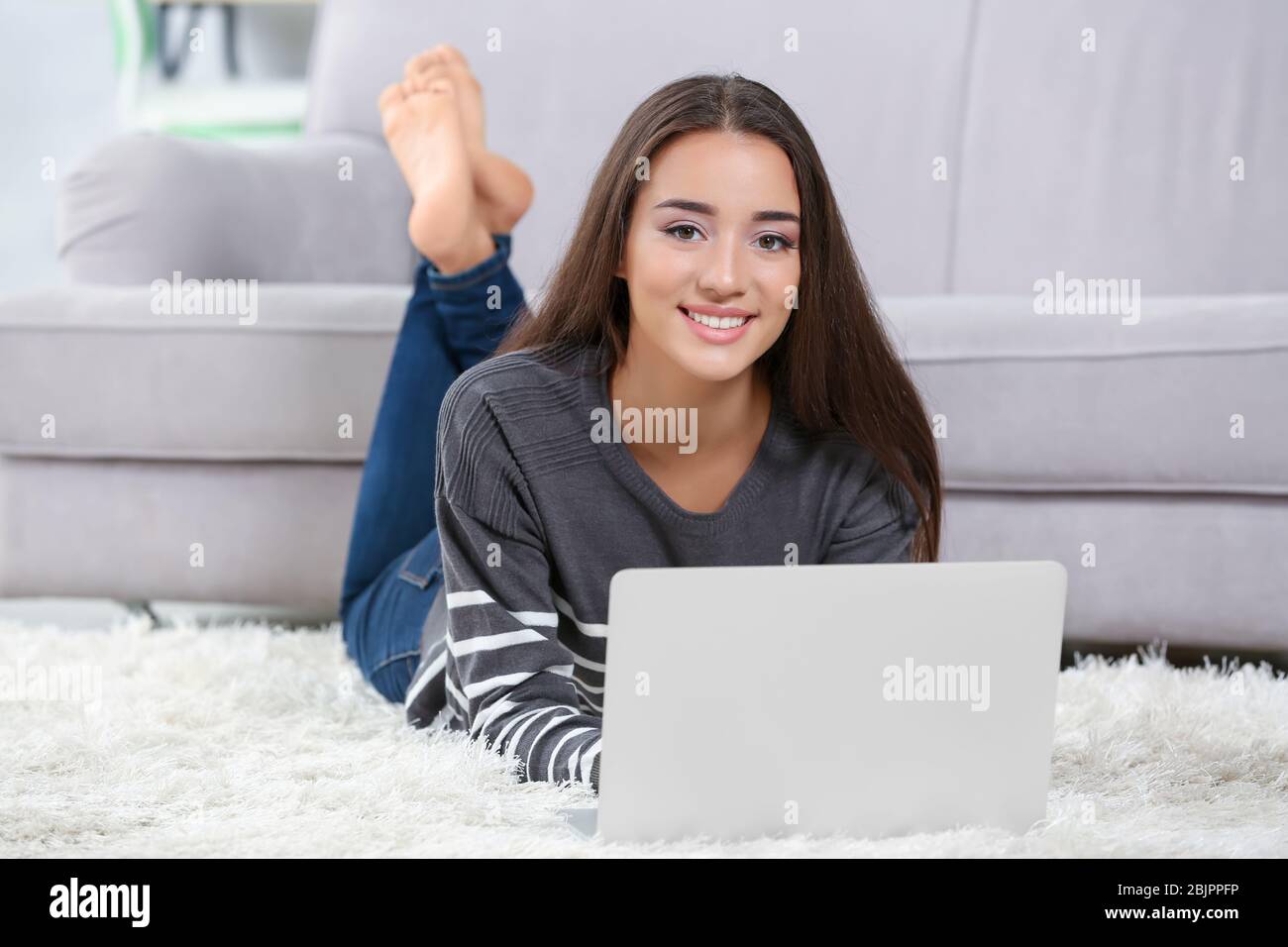 Young woman with modern laptop on carpet at home Stock Photo Alamy