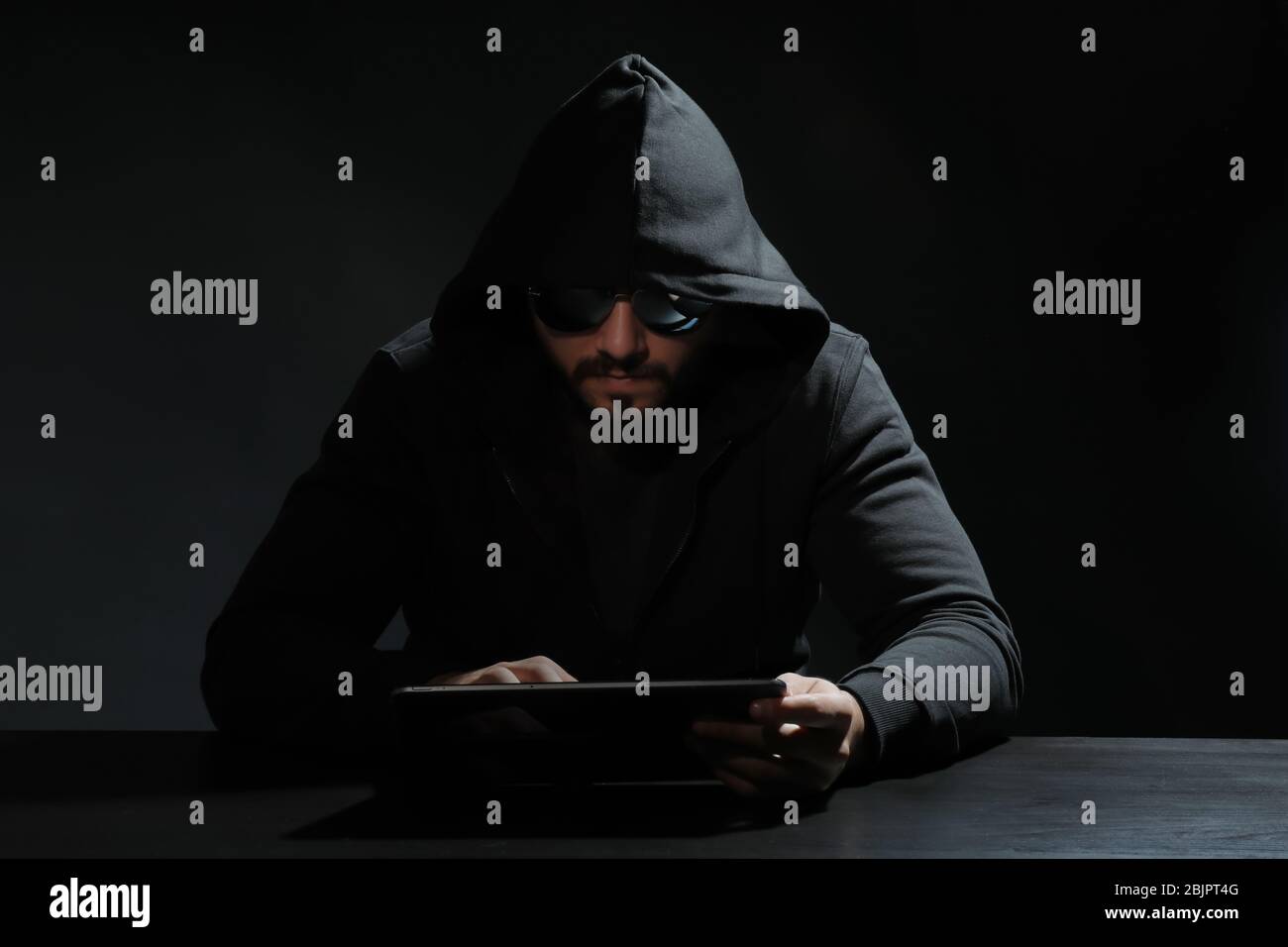 Hacker using tablet on dark background Stock Photo