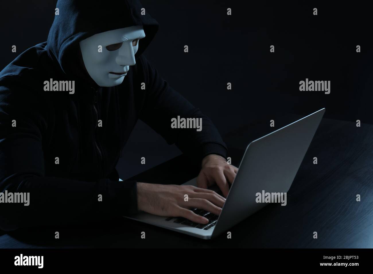 Hacker using laptop on dark background Stock Photo