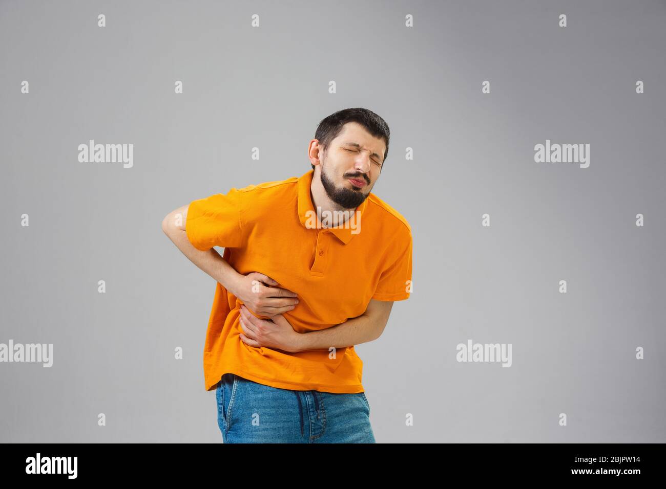 Young man suffering from flank pain on grey background Stock Photo