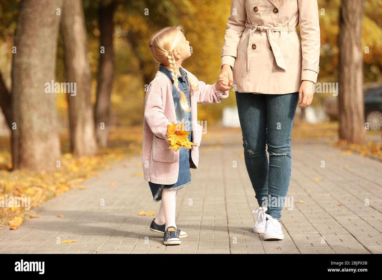 Little girl and mother walking together in park Stock Photo - Alamy