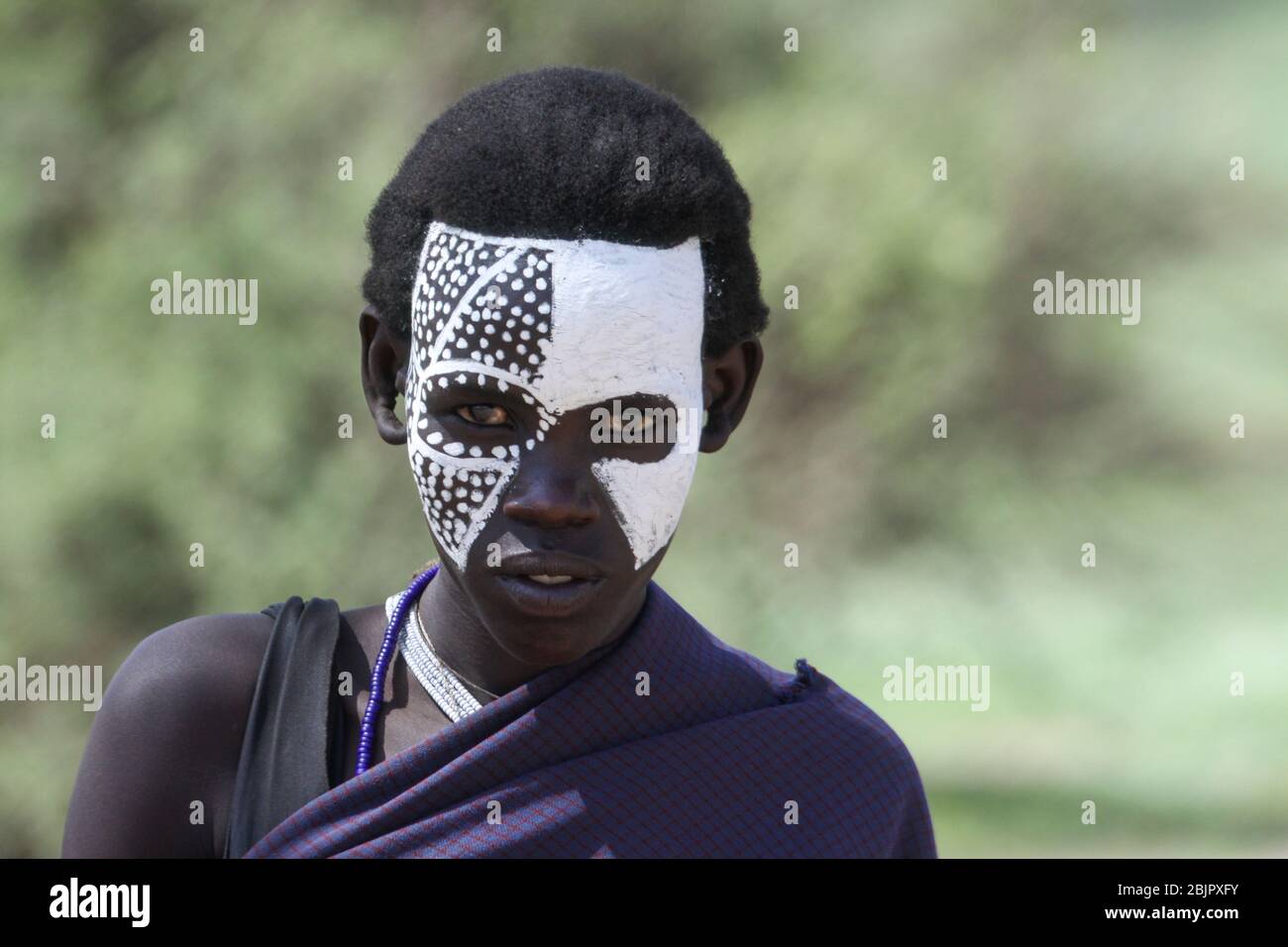A teenage Maasai with painted face after the 'emorata' ceremony, which is the circumcision and right of passage to become a member of the warrior or ' Stock Photo
