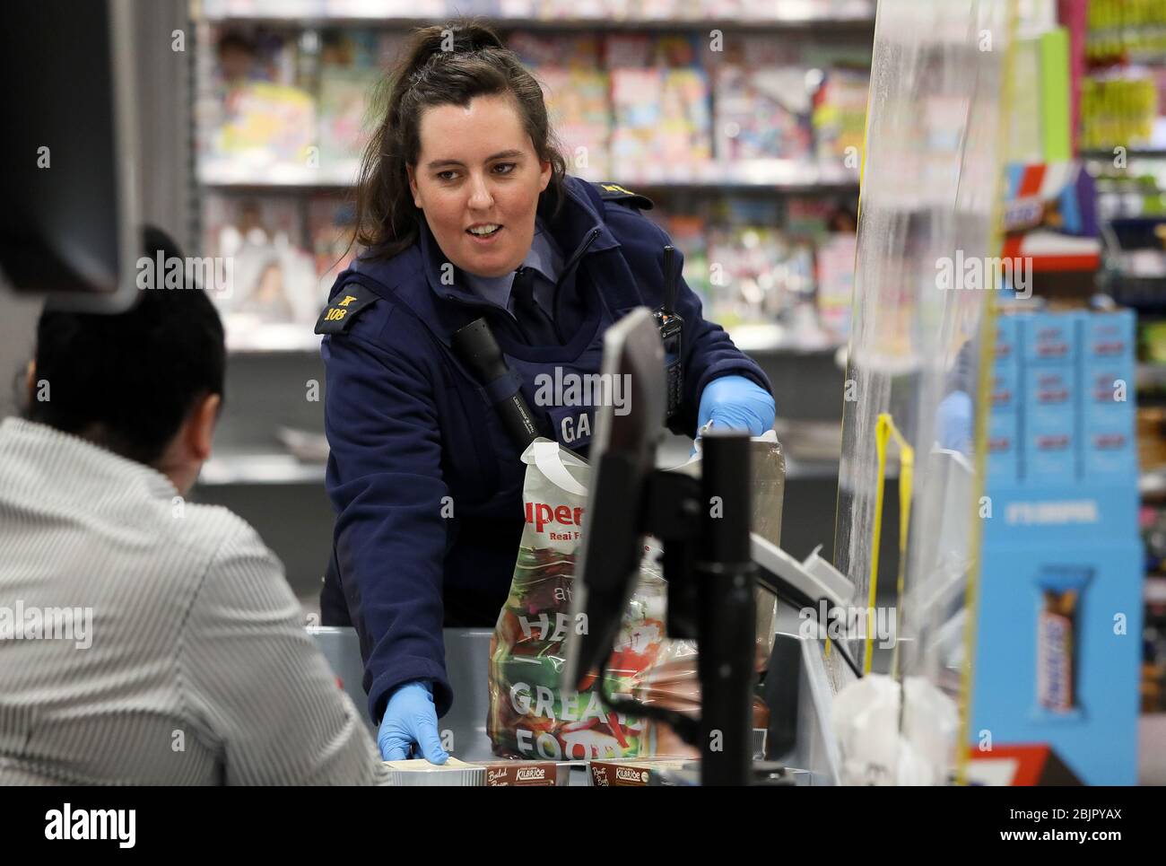 Community Garda Louise O'Sullivan at the checkout in SuperValu in Finglas. Members of An Garda continue to engage in a wide range of community activites, in an effort to help people through the Covid-19 pandemic, including delivering medicine for people self-isolating, collecting pensions, and doing the shopping for people cocooning. Stock Photo