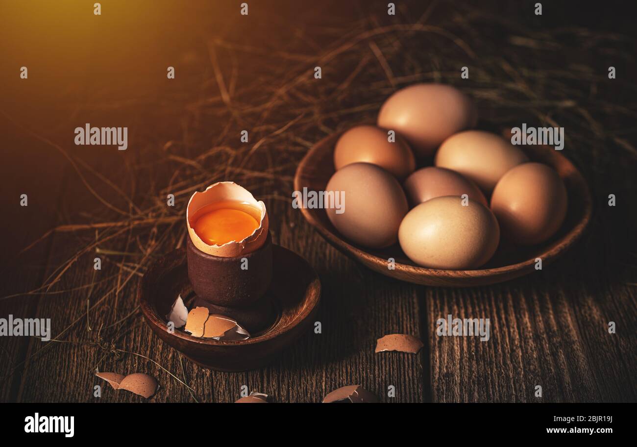 Still life of cracked raw farm egg on vintage wooden background Stock Photo