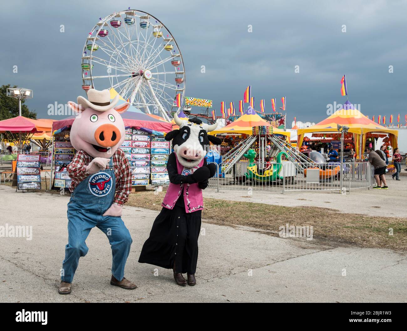 Costumed cow and pig walk the carnival grounds at Rodeo Austin, the