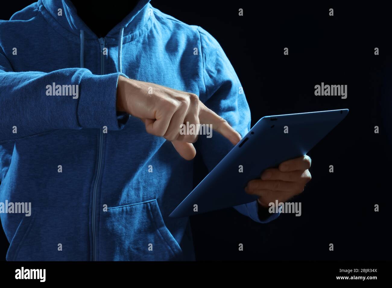 Professional hacker with tablet on dark background Stock Photo