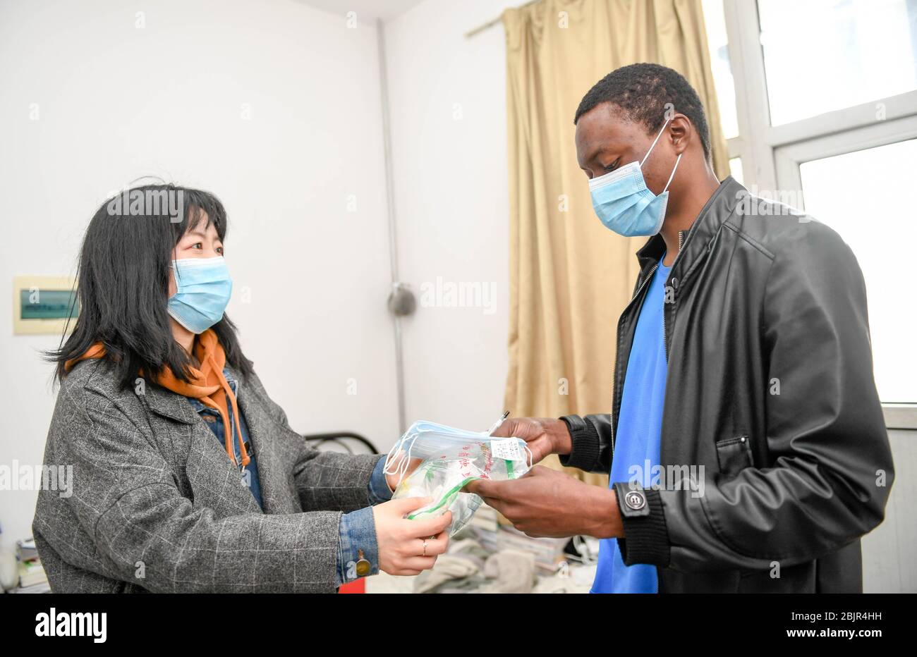 (200430) -- CHANGCHUN, April 30, 2020 (Xinhua) -- Mustapha (R) receives masks and herbal tea from the school in Changchun University of Chinese Medicine in Changchun, northeast China's Jilin Province, April 30, 2020. Mustapha Abdul Raheem has experienced two epidemics in the past six years: one was the Ebola in West Africa in 2014, during which he witnessed sufferings and aspired to study medicine; the other was the COVID-19. This time as a medical student in China, he was better prepared, both professionally and mentally. TO GO WITH 'Feature: An African medical student's fight against COVID-1 Stock Photo