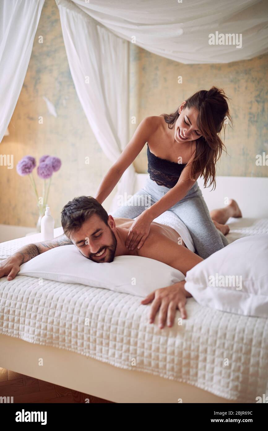 Young man and woman relaxing in bedroom.Happy girl massage her boyfriend  Stock Photo - Alamy