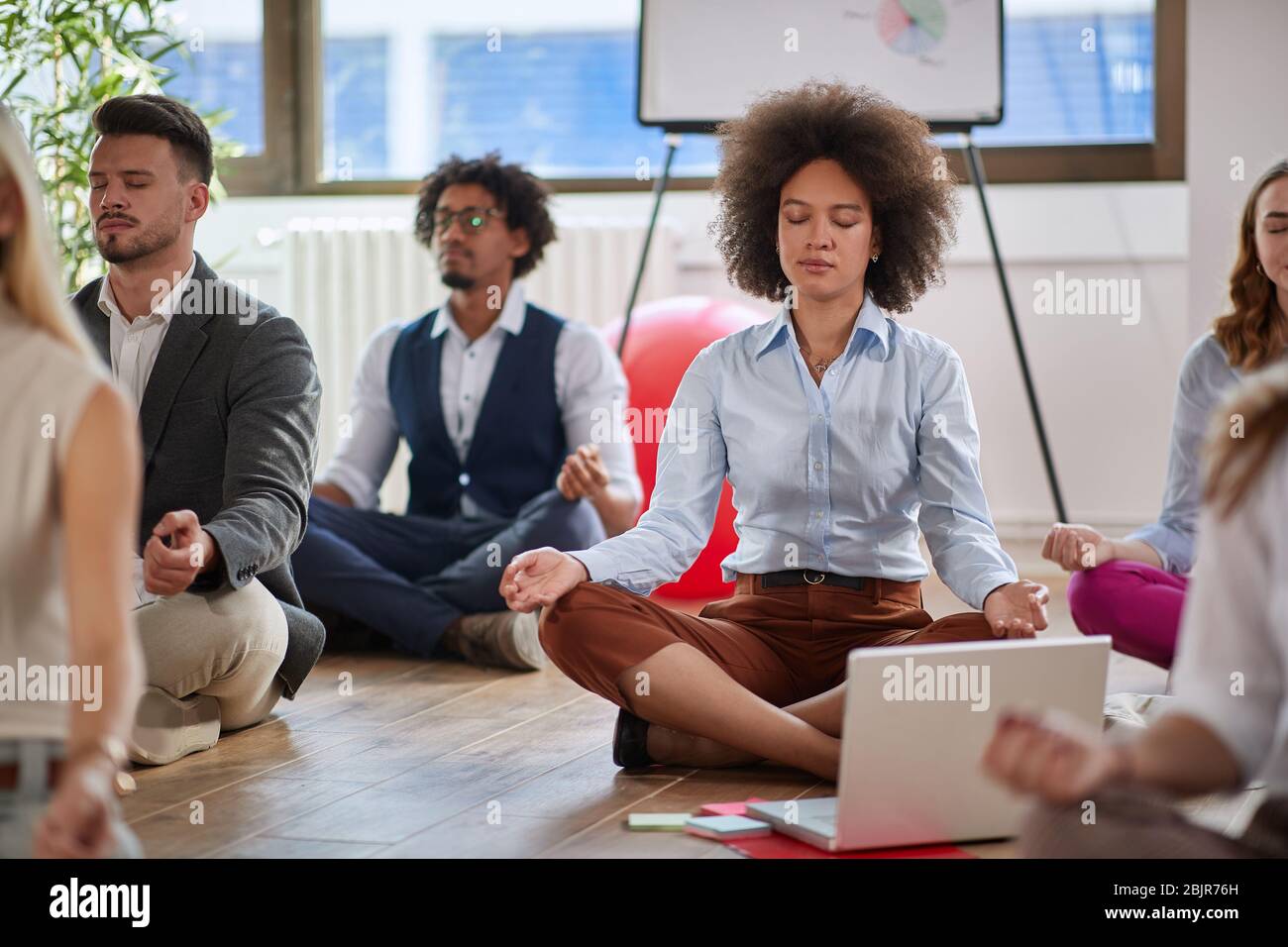 colleagues meditating at work, focus on female afro-american. togetherness, teambuilding, increasing productivity, relaxing. Stock Photo