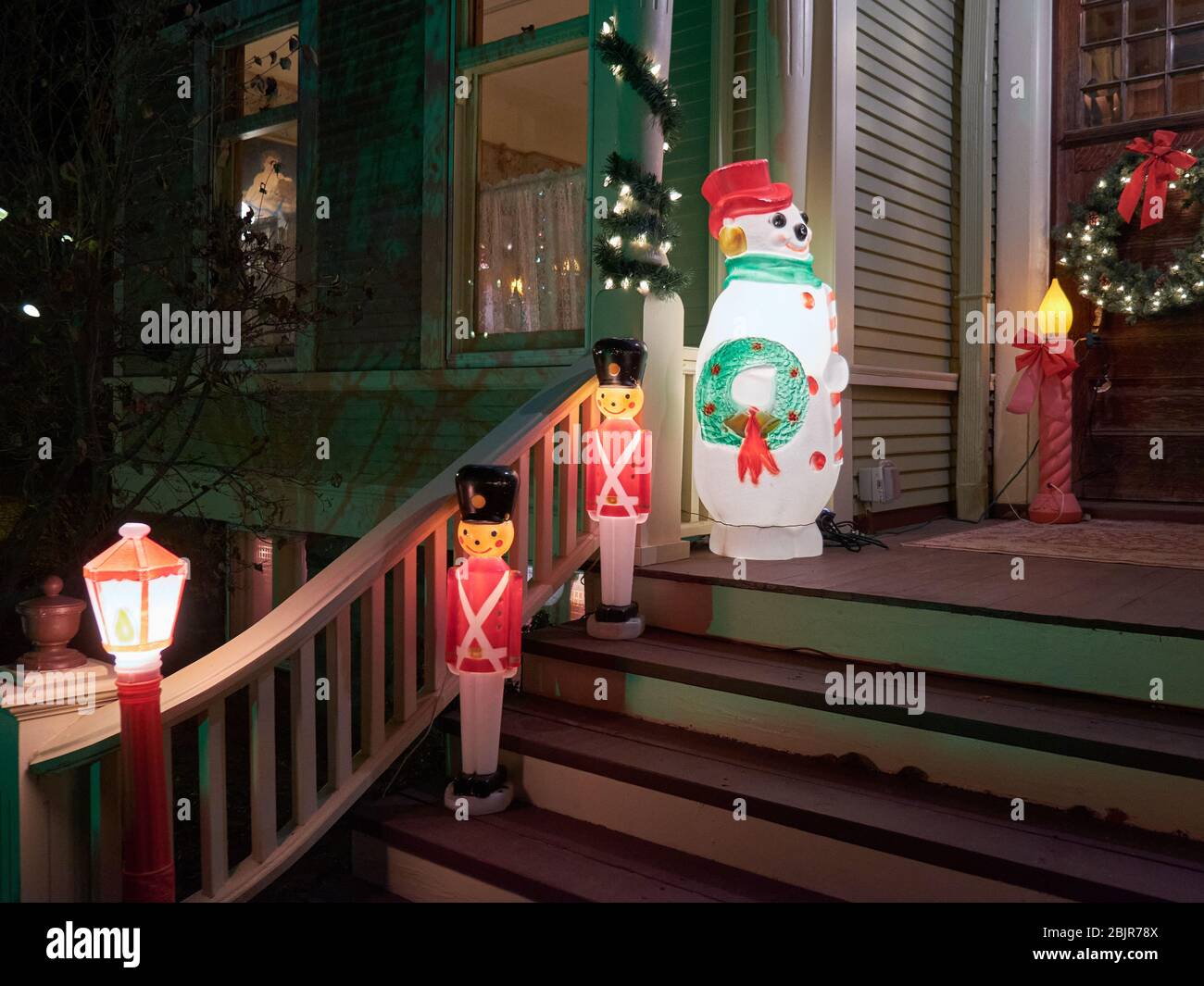 Christmas seasonal holiday blow mold decorations on stairs leading into a house. Toy soldier, snowman, candle and streetlight. Stock Photo